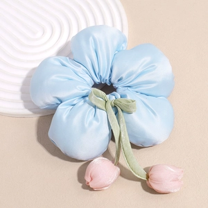 Détail d'un chouchou en satin bleu avec des pendentifs tulipes roses et un nœud vert