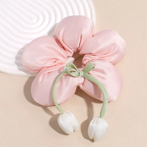 Détail d'un chouchou floral en satin rose avec pendentifs tulipes blanches et nœud vert