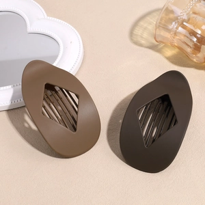 Pinces à cheveux ovales mates marron et kaki avec design évidé sur fond texturé chaleureux