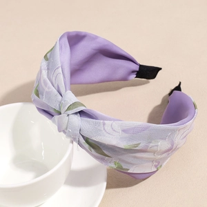Detalle de diadema anudada con flores lilas y extremos negros antideslizantes