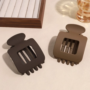 Minimalist square matte hair claws in two shades of brown on a soft aesthetic background