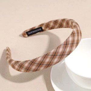 Close-up of brown plaid headband featuring a handmade fabric label on the inner side