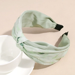 Detalle de diadema de seda verde claro con elegante estampado botánico floral en la tela