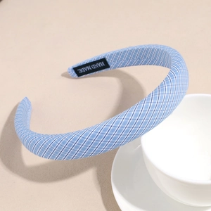 Detail of blue and white checkered fabric headband with a black HAND MADE woven label