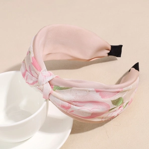Vista detallada de la diadema con nudo floral rosa con textura de satén de seda y rosas