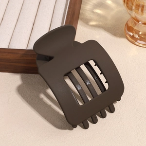 Macro detail of the coffee-colored matte square hair claw clip on wooden jewelry box