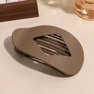 Détail de la grande pince à cheveux ovale marron moka mat sur fond texturé crème