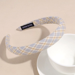 Detail of blue and yellow plaid headband with a black Hand Made woven label