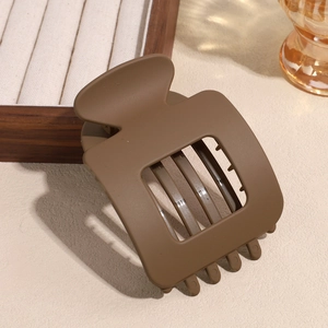 Detailed view of matte dark coffee rectangular hair claw clip on a wooden display tray