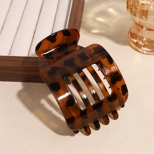 Detail of tortoiseshell matte square hair claw clip with sharp texture on warm background