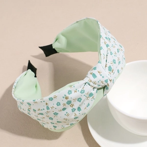 Primer plano de la diadema ancha con nudo y flores azules sobre un cuenco de porcelana