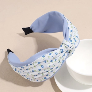 Detalle de diadema ancha floral con nudo de tela azul y puntas antideslizantes
