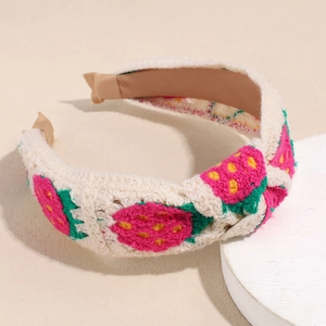 Detailed macro view of hand-knitted strawberry pattern on cream crochet headband