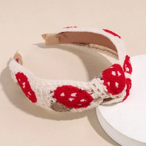 Close-up of handmade crochet headband featuring red mushroom patterns on cream knit fabric