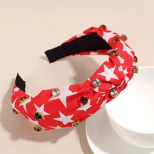 Detailed view of red knotted star headband with sparkling rhinestones and metal claw studs