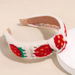 Close-up of a white knitted headband featuring red strawberry pattern and soft end tips
