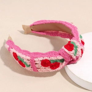 Detailed close-up of pink crochet headband with red cherry patterns and soft knit texture