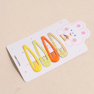 Set of four colorful droplet hair clips with polka dots and fruit prints on a card