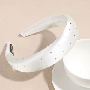 Detailed macro view of white padded satin headband featuring sparkling silver rhinestones