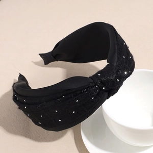 Detail view of black headband showing satin texture and sparkling rhinestone embellishments