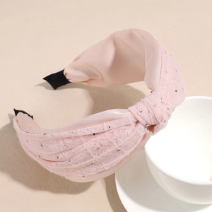 Detailed shot of pink lace headband with silver rhinestones and elegant top knot design