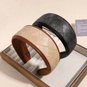 Serre-tête large en cuir PU avec texture losange tressée sur un plateau à bijoux chic