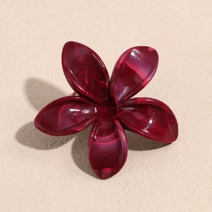 Detailed macro of a wine red five-petal flower hair claw with marble texture on beige background