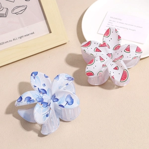 Floral acrylic hair claws featuring watermelon and blueberry patterns on a beige surface