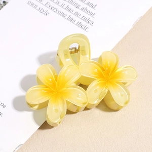 Gros plan d'une pince à cheveux fleur de frangipanier jaune aux pétales translucides