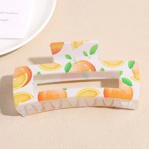 Detail view of a floral hair claw clip with orange fruit patterns and sturdy resin teeth