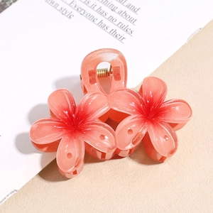 Détail d'une pince à cheveux en forme de fleur avec dégradé rose-orange et ressort doré