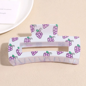 Detailed view of white square hair claw clip with purple grape print on textured surface