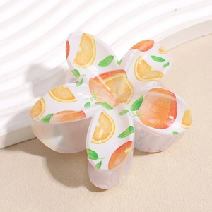 Detailed macro view of a floral hair claw clip with vibrant orange slice patterns and leaves