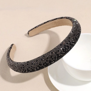 Detailed view of deep grey padded headband with dense rhinestones on white ceramic bowl