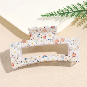 Macro view of rectangular hair claw clip with colorful floral print on cream background