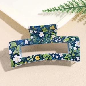 Detail view of a navy blue square hair claw clip with a white daisy floral print finish