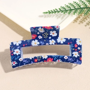 Detailed close-up of navy blue rectangular hair claw clip with floral daisy patterns