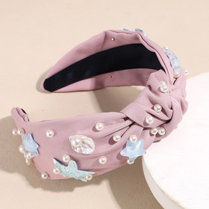 Close-up of pink knotted headband with white pearls, blue resin starfish and shell charms