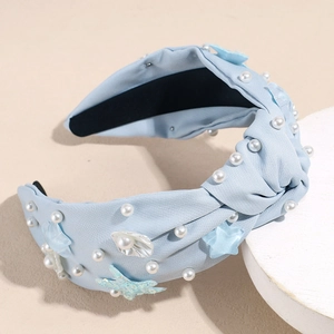 Detail of light blue knotted headband with white pearls and decorative sea stars