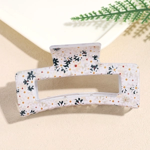 Detail of a rectangular hair claw clip with yellow daisy floral print on cream base