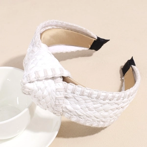 Close-up of a white knotted straw headband with woven texture and a soft silk lining