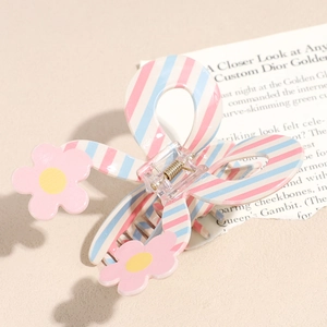 Dettaglio di un fermaglio per capelli a righe rosa e blu con accenti floreali