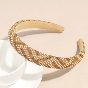 Détail d'un serre-tête large de luxe avec perles et strass posé sur une tasse en céramique