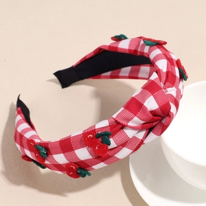 Detail of red and white checkered headband with embroidered cherries and top knot