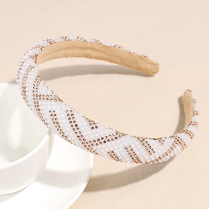 Détail du serre-tête large orné de perles et strass champagne sur tissu beige clair