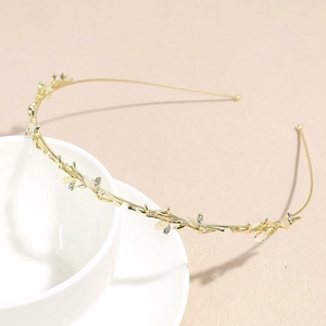 Close-up of golden leaf headband with rhinestones and white opals on a ceramic cup