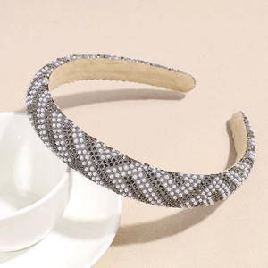 Détail d'un serre-tête large de luxe avec perles blanches et strass gris en motif de grille
