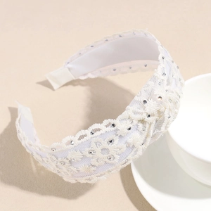 Gros plan du bandeau en dentelle crème avec strass scintillants et détails floraux