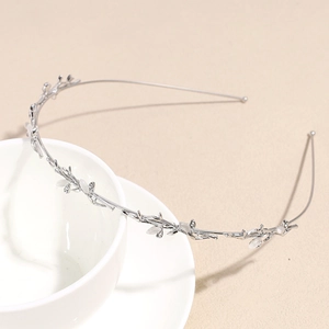 Detail of silver leaf headband with rhinestones and white opal-like stones on a textured surface