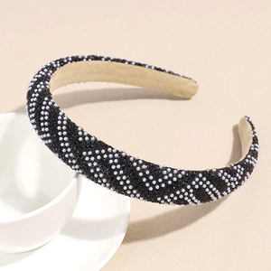 Détail du serre-tête noir avec perles blanches et strass posé sur une tasse blanche